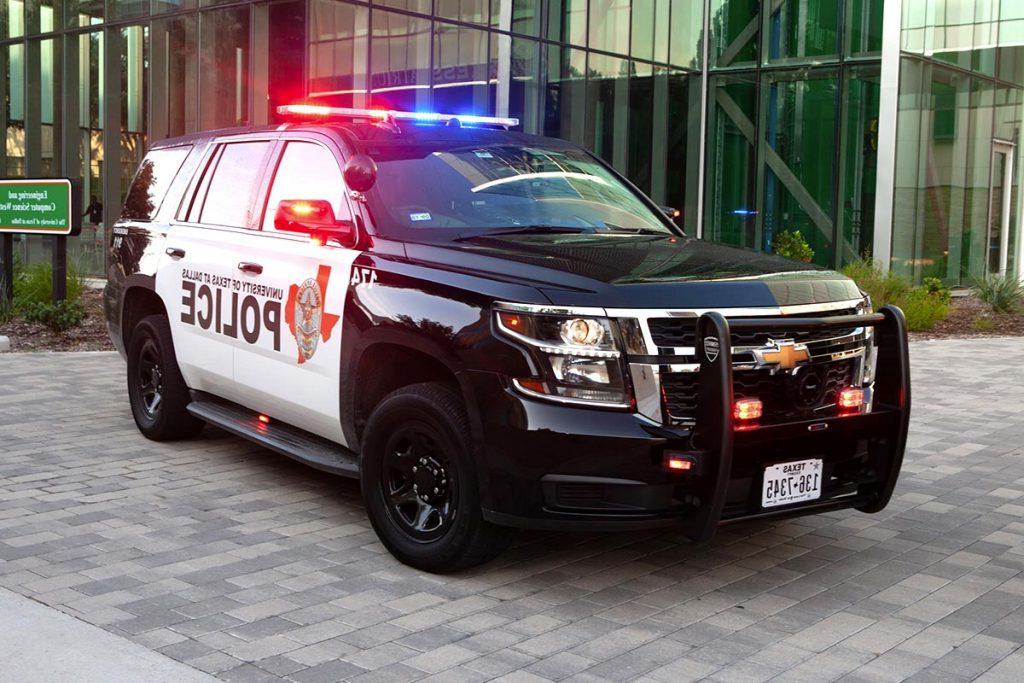 A police SUV with its lights on in front of the ECSW building.